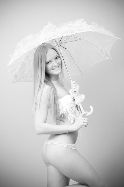 회색 배경에 레이스 우산이 있는 수영복을 입은 아름다운 소녀의 초상화