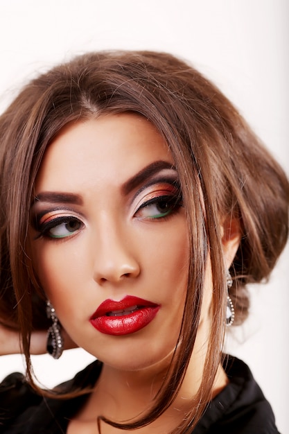 Portrait of beautiful girl touching her face with bright pink makeup on grey background. Concept of beauty and fashion