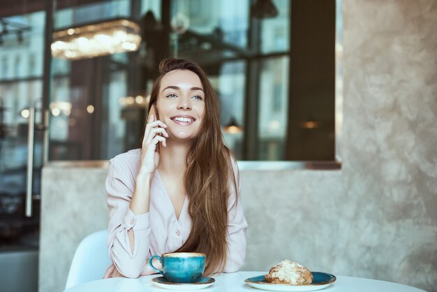 カフェで彼女の携帯電話を使用して美しい少女の肖像画。