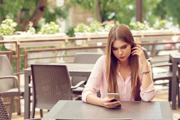 カフェで彼女の携帯電話を使用して美しい少女の肖像画。