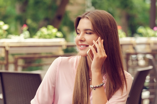 カフェで彼女の携帯電話を使用して美しい少女の肖像画。