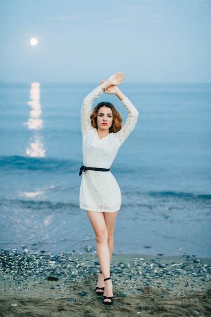 Portrait of a beautiful girl in a white dress on the beach