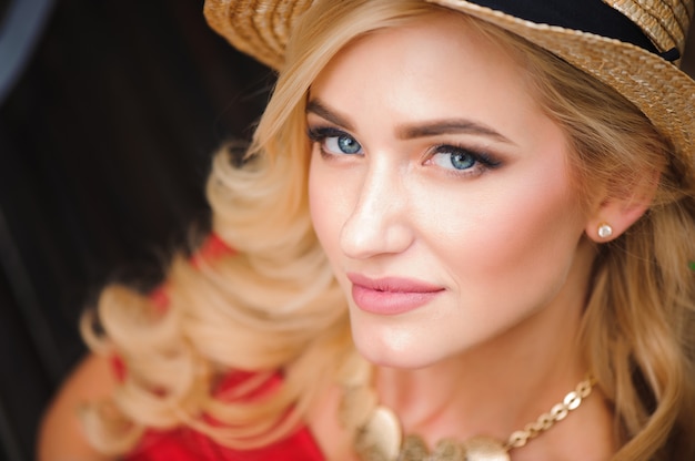 Portrait of a beautiful girl with blond hair. Stylish girl is sitting on a park bench.