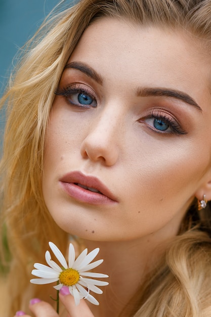 Portrait of a beautiful girl with a Daisy in her hands, beautiful make-up