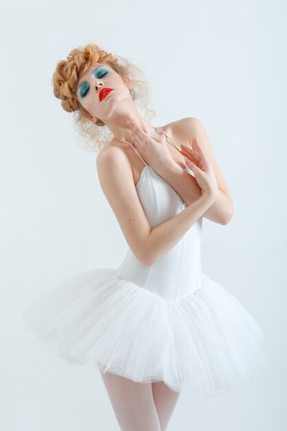 Portrait of a beautiful girl with fashion makeup  red lips, stylish hairstyle. In ballet dress. 