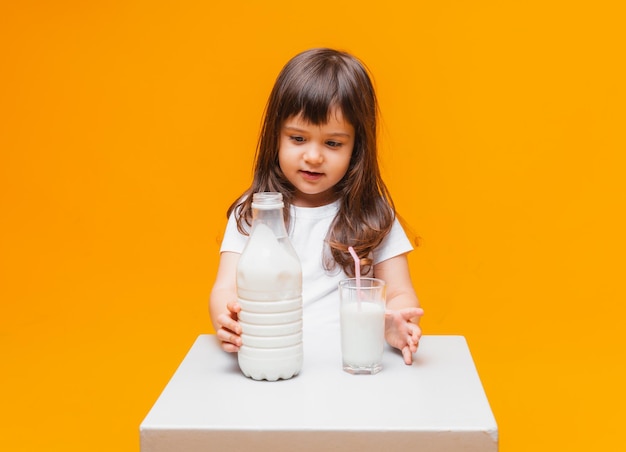 Portrait of beautiful girl with glass of milk on yellow background