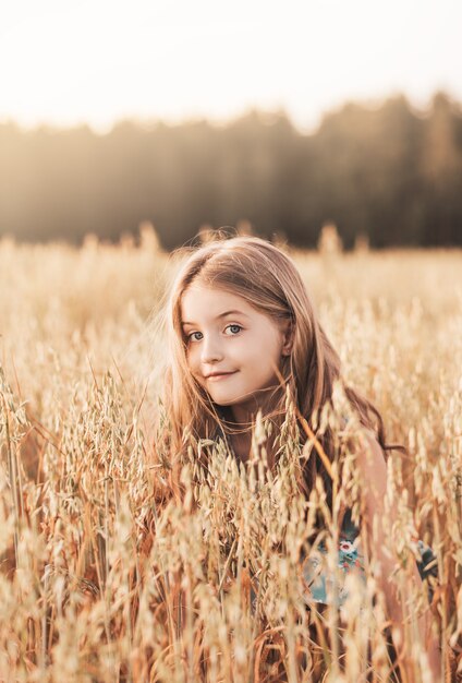 Ritratto di una bella ragazza con i capelli lunghi su un campo dorato al tramonto