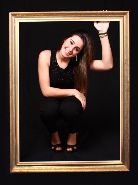 portrait of a beautiful girl with long straight hair with a picture frame and black background