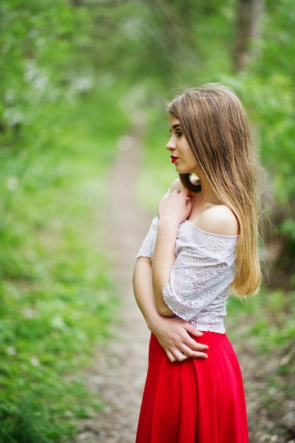 Portrait of beautiful girl with red lips at spring blossom garden wear on red dress and white blouse