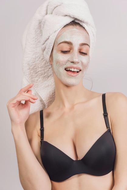 Photo portrait of beautiful girl with a towel on her head snd facial mask, relaxing at home