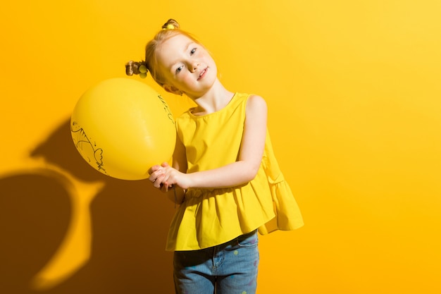 Portrait of a beautiful girl in a yellow blouse and blue jeans.