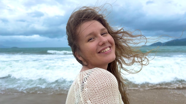 Portrait of beautiful girl young happy positive cheerful joyful woman enjoying vacation on sea ocean walking on summer beach in tropical country smiling having fun laughing in knitted sweater