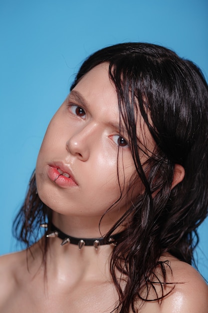 Portrait of beautiful Gothic woman with piercings and other accessories on blue