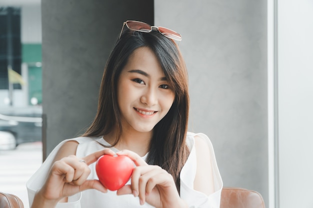 Portrait of beautiful happy Asian woman smiling and holding a red heart