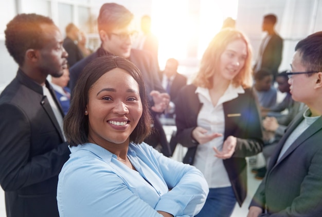 Портрет красивой счастливой черной женщины на фоне других бизнесменов в офисе