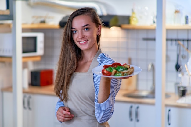 Ritratto di una bella donna di cucina sorridente gioiosa carina felice con un piatto di insalata fresca