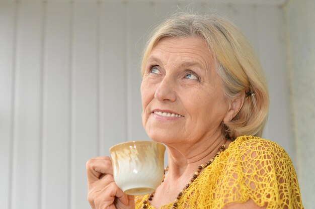 Portrait of a beautiful happy elderly woman with a cup of tea