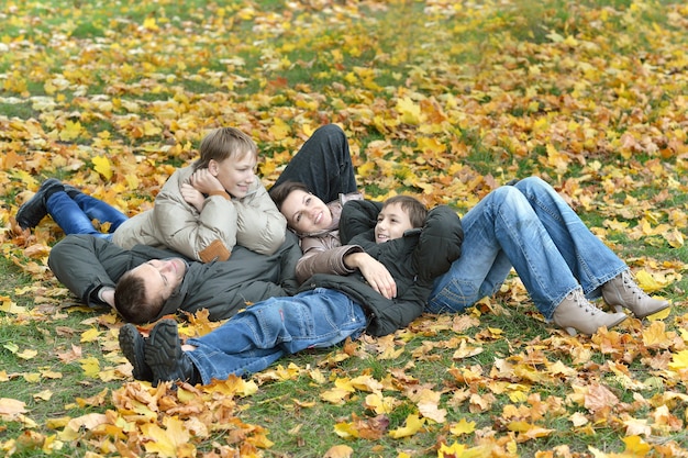 Portrait of a beautiful happy family lying in autumn park