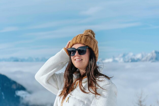 portrait of beautiful happy girl wearing winter clothes standing in amazing mountains on sunny day
