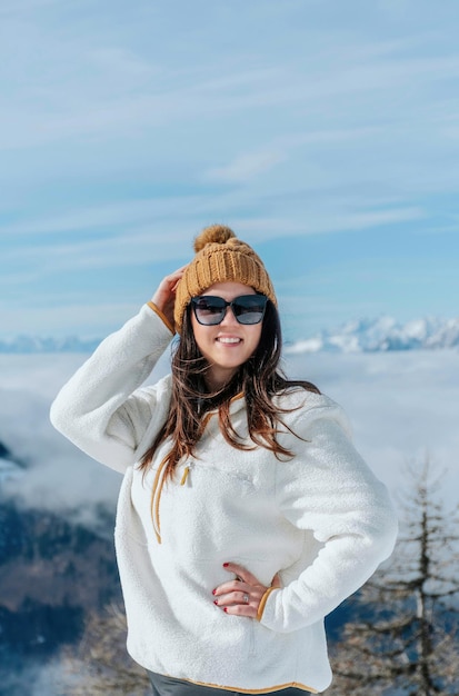 portrait of beautiful happy girl wearing winter clothes standing in amazing mountains on sunny day