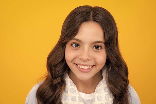 Portrait of beautiful happy smiling teenage girl on yellow studio background