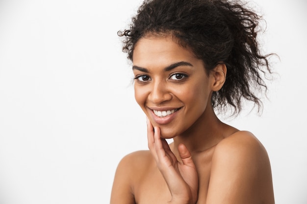 Photo portrait of a beautiful happy young african woman posing isolated over white wall.