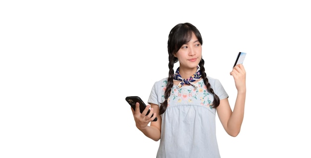 Portrait of beautiful happy young asian woman in denim dress holding credit card and smartphone on white background studio shot