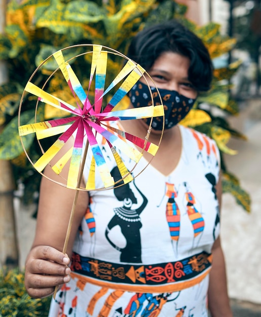 Photo portrait of a beautiful indian girl in ethnic casual and protective face mask holding a pinwheel