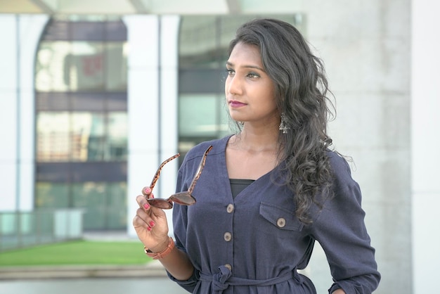 Portrait of a beautiful Indian woman fashion model holding sunglasses with her hand