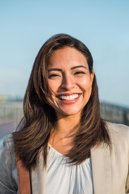 Portrait of a beautiful latin woman smiling outdoors with sunset light Vertical image