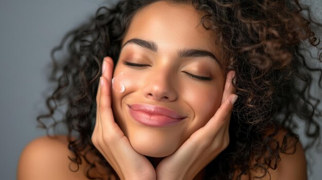 Photo portrait of beautiful latin woman touching her clean and healthy face against grey background smiling hispanic woman with natural makeup feeling healthy skin with eyes closed beauty care pampering