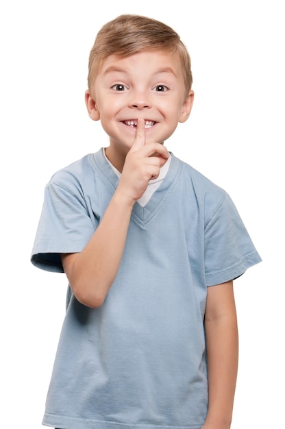 Портрет красивого маленького мальчика с жестом молчания на белом фоне