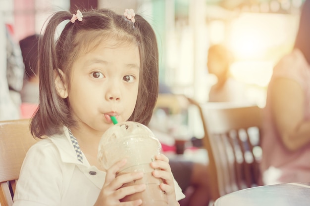 portrait of a beautiful little cute girl drinking iced chocolate in coffee shop