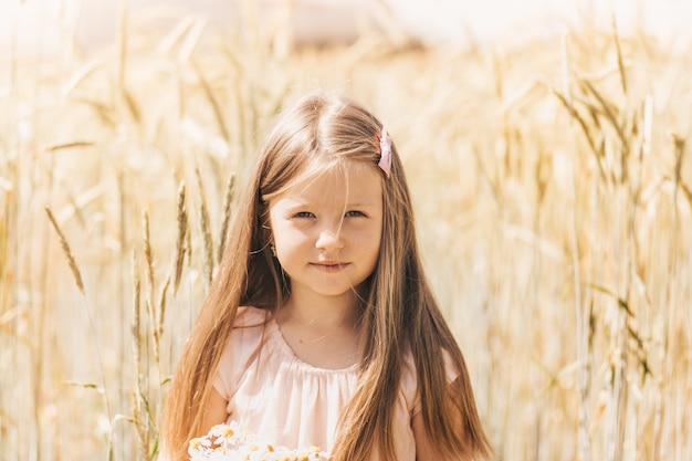 Portrait of a beautiful little girl blonde in a wheat field