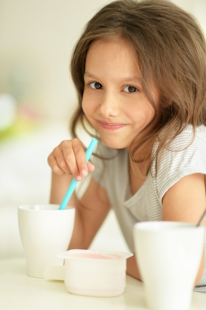 Portrait of a beautiful little girl drinking at home