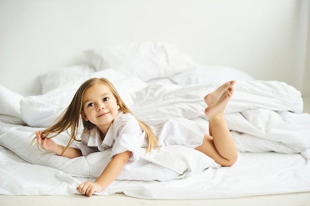 A portrait of beautiful little girl in the morning bedroom