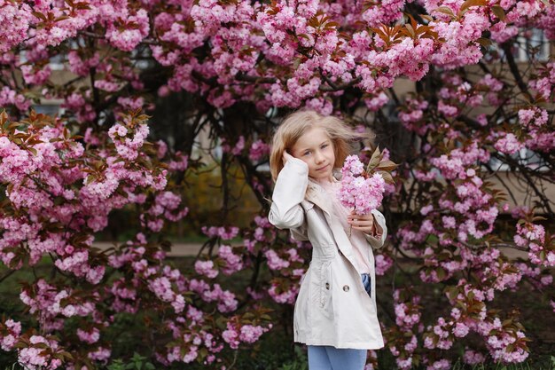 Portrait of a beautiful little girl in pink cherry blossoms Women's Day celebration
