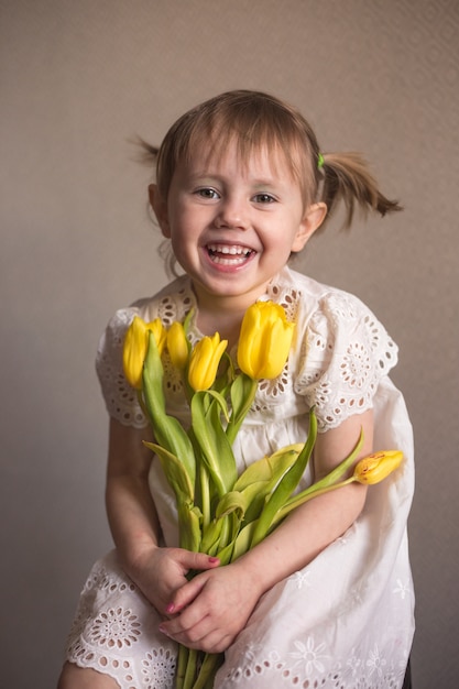 黄色いチューリップの花の花束を持つ美しい少女の肖像画