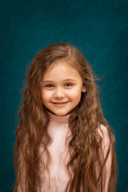 Portrait of a beautiful little girl with long hair on a blue background