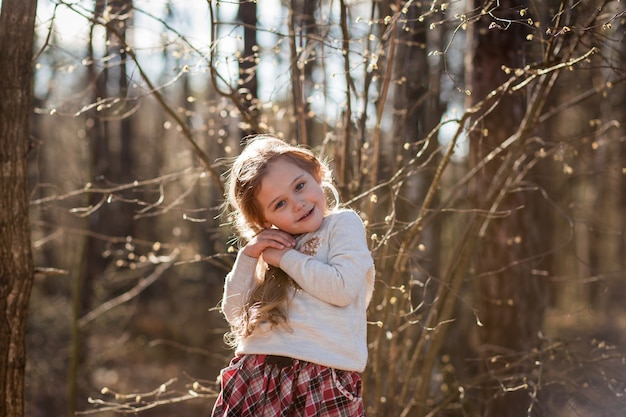 portrait of a beautiful little girl with long hair in the woods on nature