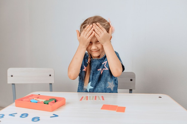 Photo portrait of a beautiful lovely princess girl sitting at a table surrounded by a large number of puzzles and closing her eyes from excitement. progress concept. photo with noise