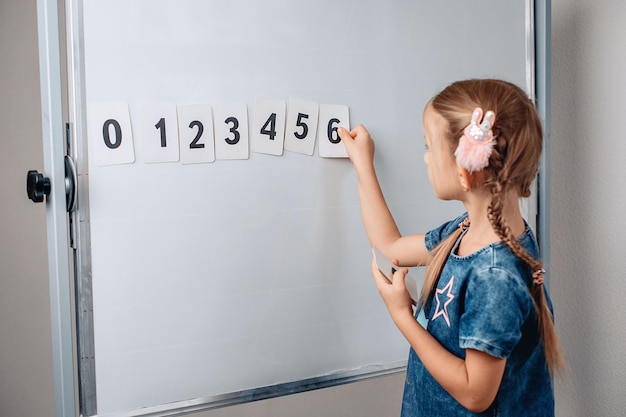 Portrait of a beautiful lovely smart kid arranging numbers in the correct order. Lovely child holding a card with number 6. Concept of knowledges. photo with noise