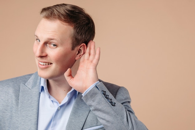 Portrait of beautiful man in grey and blue office suit listens for something and smiles