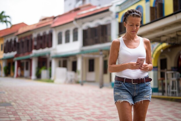 Portrait of beautiful mature tourist woman enjoying life while travelling in Singapore city