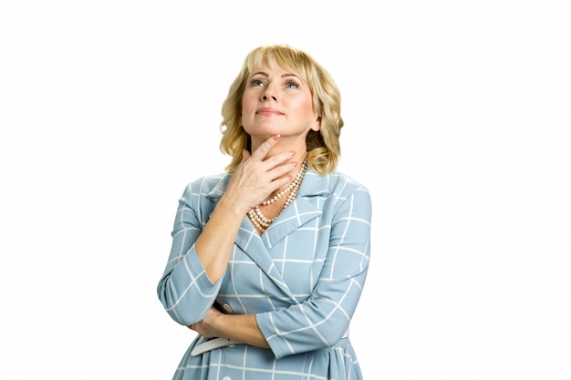 Portrait of beautiful mature woman. Adult lady looking upwards touching her neck while standing on white.