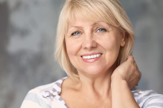 Portrait of beautiful mature woman on grey background