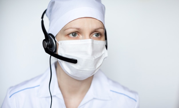 Ritratto di bella donna medica che indossa maschera protettiva con microtelefono.