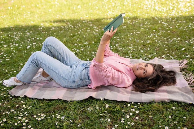 Photo portrait of beautiful middle aged woman relaxing with book on plaid outdoors