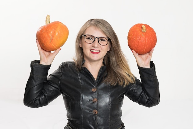 Portrait of beautiful middleaged strict woman in a leather jacket and glasses with pumpkin ready for halloween celebration mockup for postcard and invitation or advertisement