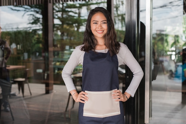 Portrait of beautiful mixed race cafe owner smiling proudly in their shop